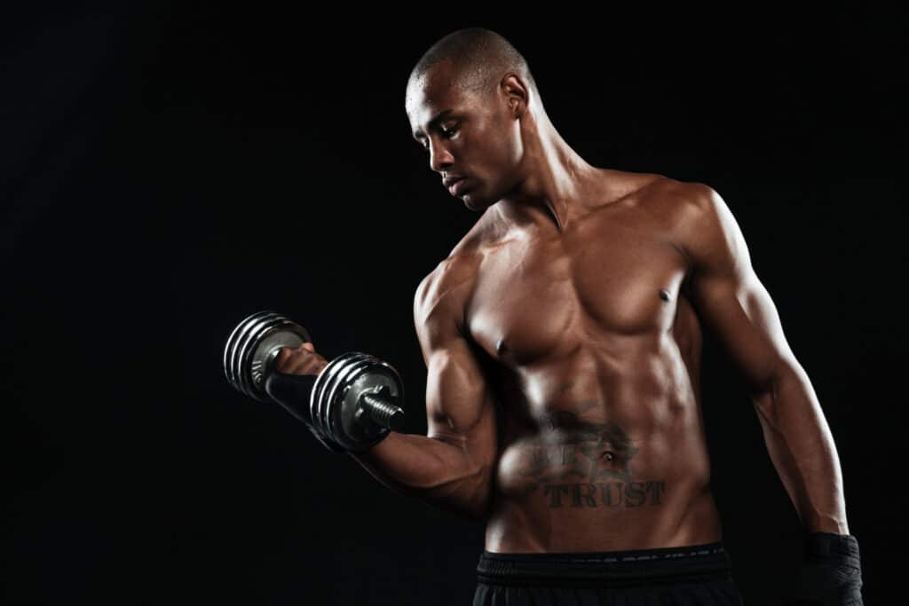 A half naked young afroamerican sportsman lifting dumbbells