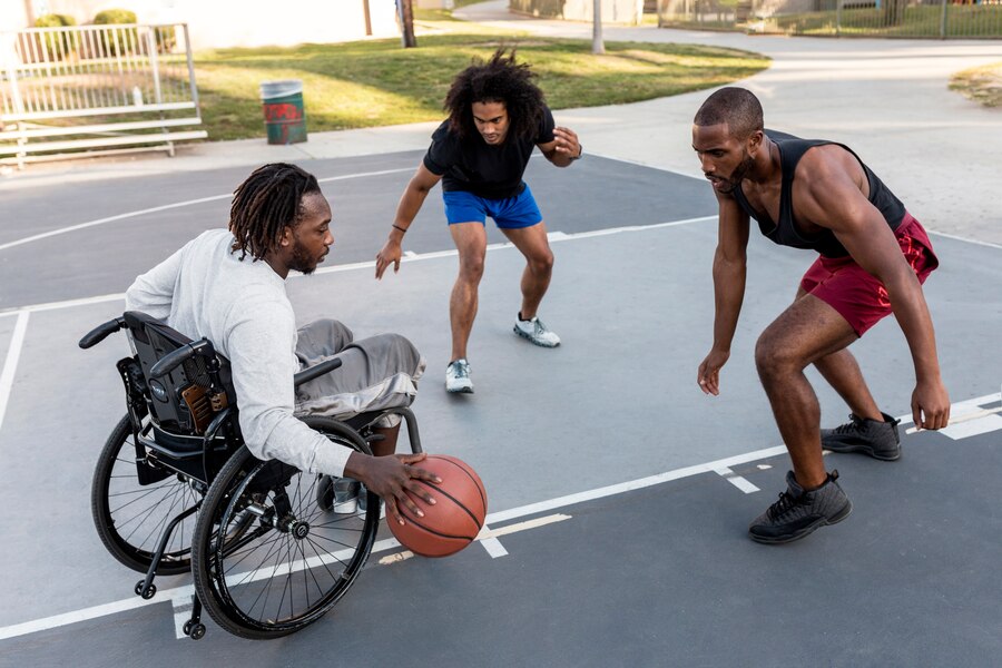 Un homme handicapé en fauteuil roulant joue au basket-ball avec ses amis à l'extérieur