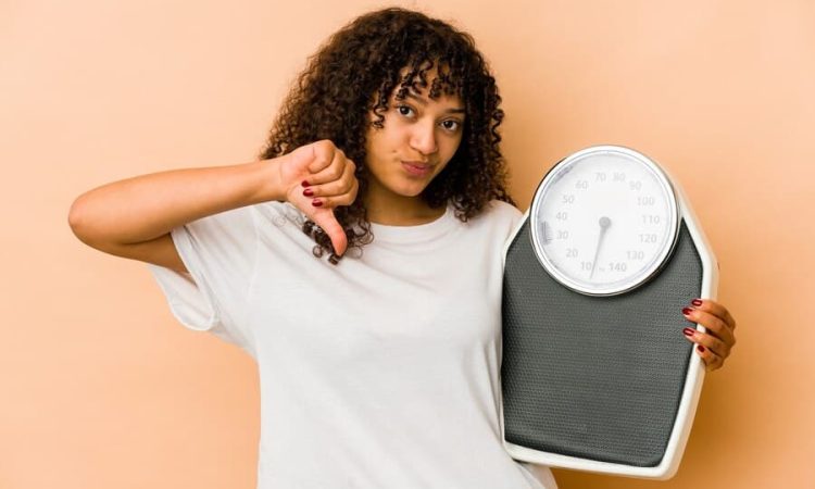 young-african-american-afro-woman-holding-scale-showing-dislike-gesture-thumbs-down-disagreement-concept_1187-101385